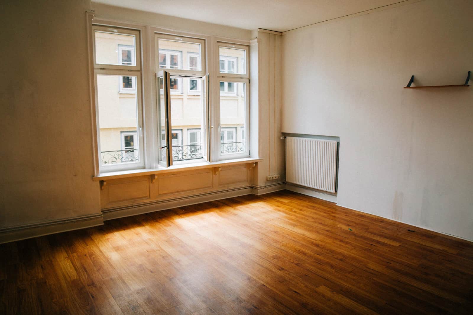 Empty East London-style room with clean wooden floor and tall windows